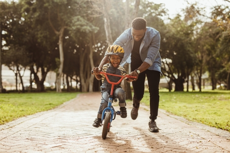 father teaching son to ride a bike